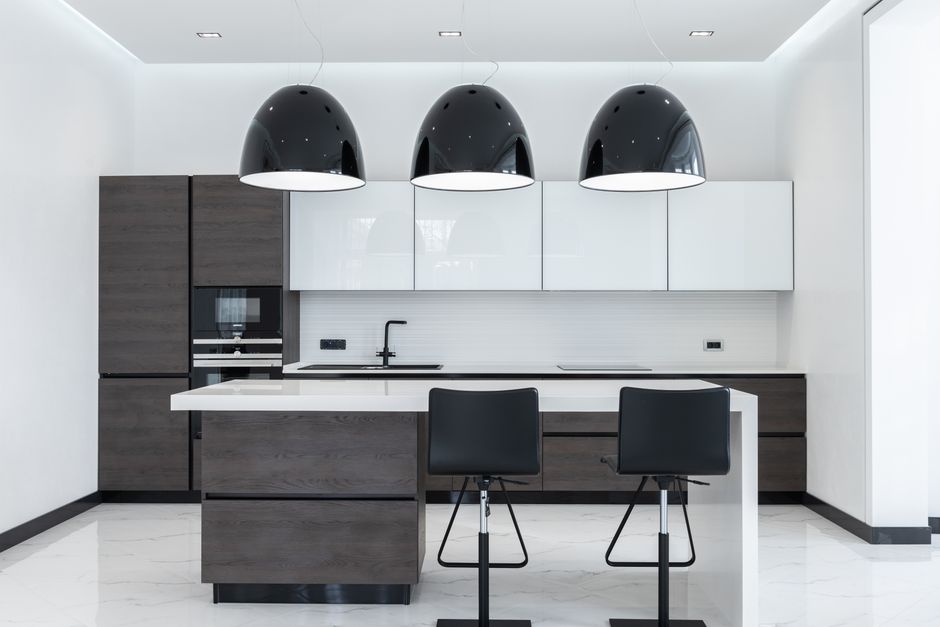 Kitchen with pendant lamps over a table and wooden cabinets.